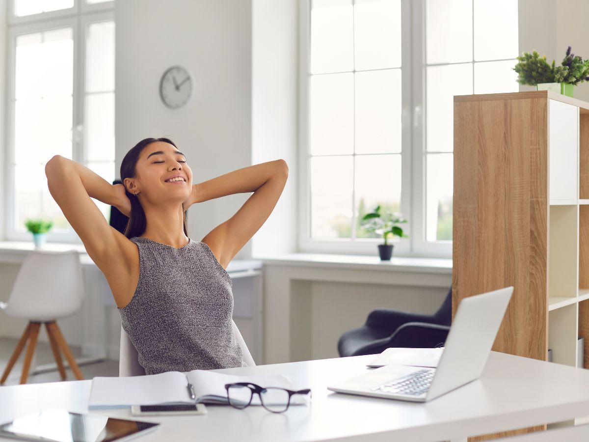 Entspannt arbeitende Frau sitzt an einem Schreibtisch, umgeben von einer harmonischen und gut organisierten Arbeitsumgebung, die Ruhe und Fokus ausstrahlt.